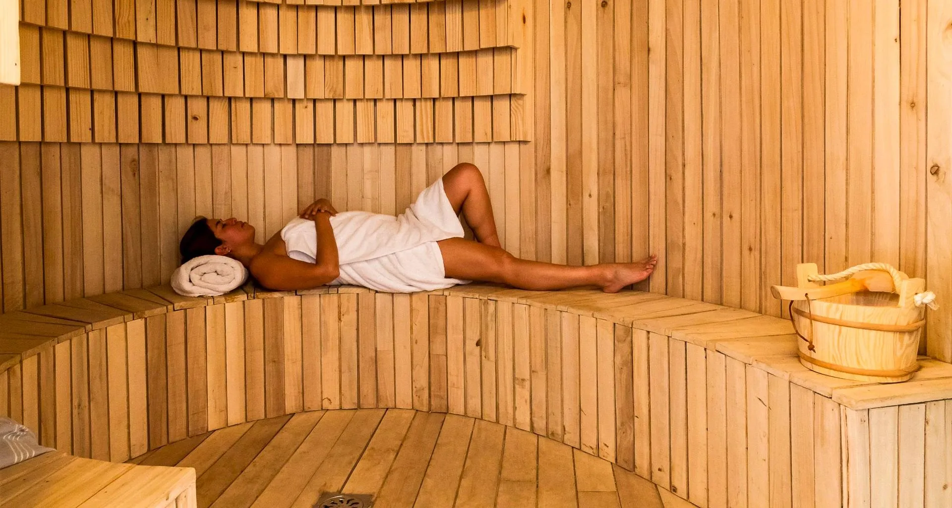 Woman lies on bench in sauna