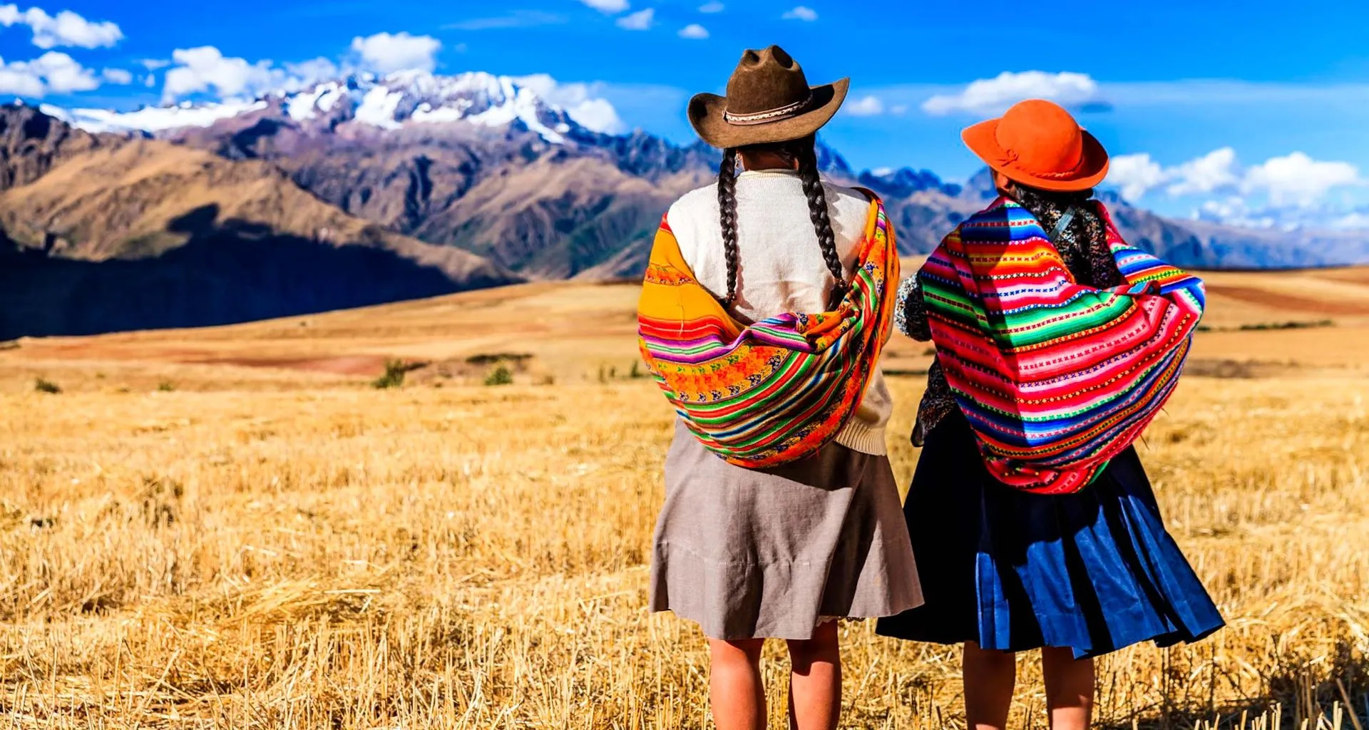 Two women din colorful shawls stand on Peru plain