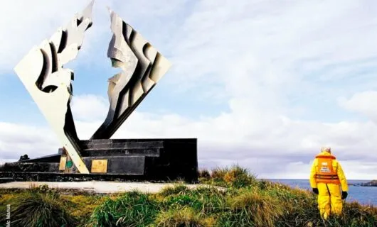 Man in yellow suit stands near sculpture