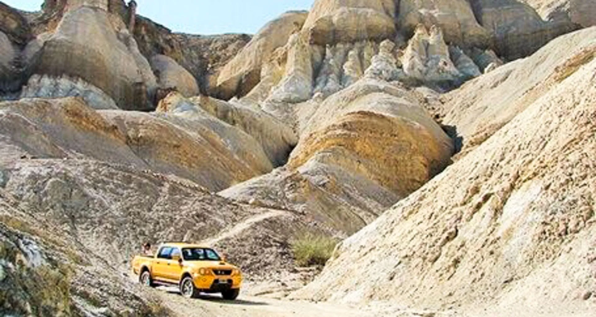 Yellow truck drives through rocky South America valley