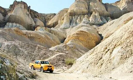 Yellow truck drives through rocky South America valley