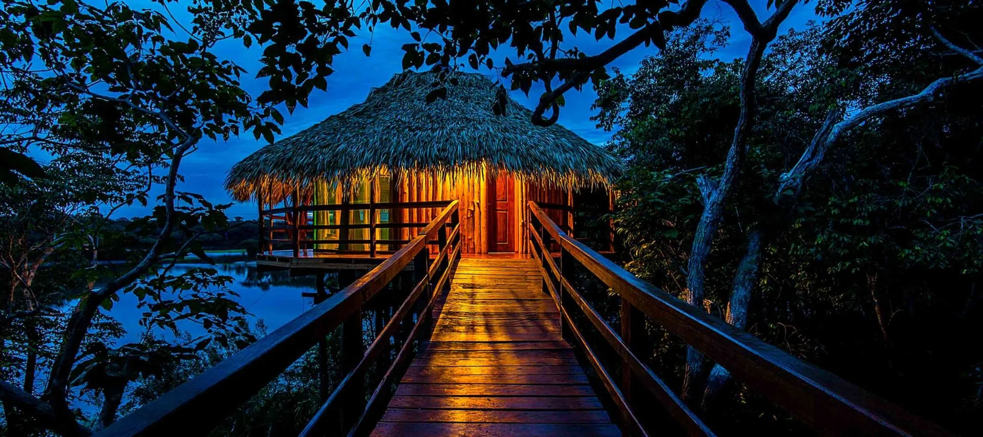 Path through trees to lit amazon jungle lodge bungalow at night