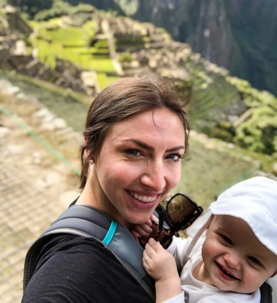 Woman holds baby on top of Machu Picchu