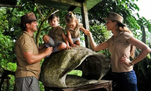 Toddlers climb on tortoise shell while parents watch