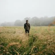 young man standing in the middle of a field