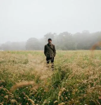 young man standing in the middle of a field