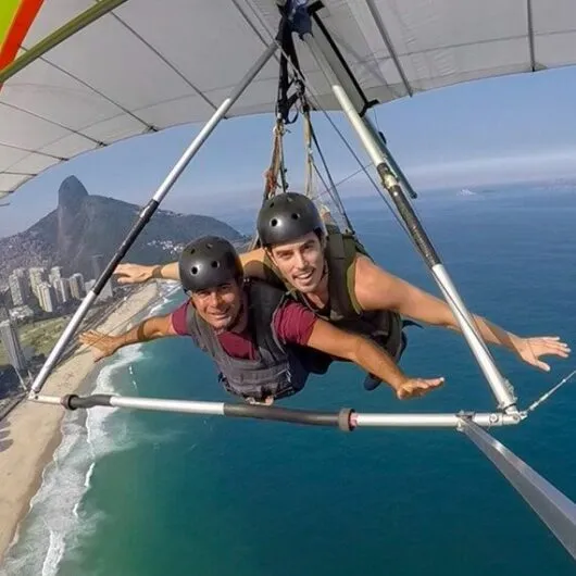 Two men visiting brazil and paragliding over water
