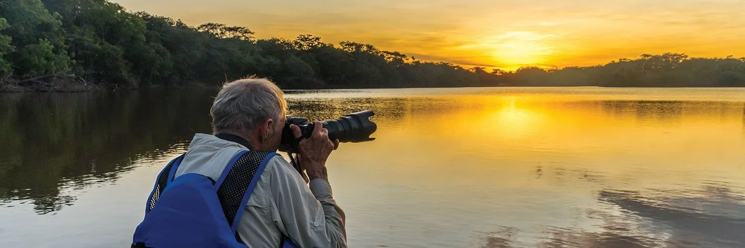 explorer taking a picture of the amazon river at sunset