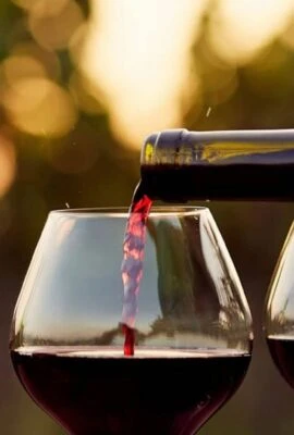 man pouring two wine glasses with red wine