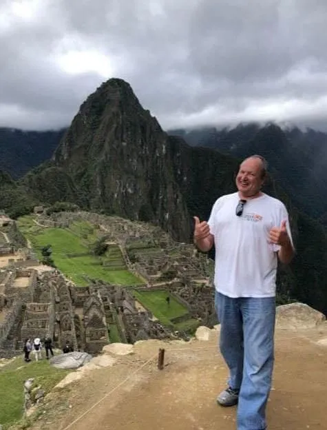 Man enjoying his vacation posing with the ruins of Machu Picchu in the background