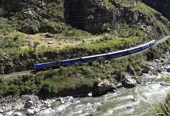 train running along the river to machu picchu