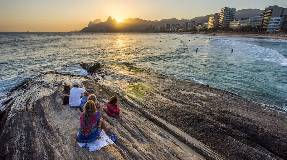 people sitting on rock at the beach near copacabana in rio de janeiro