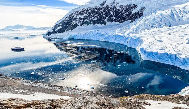 small ship near glacier in antarctica